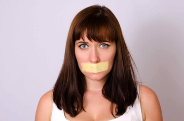 Young woman with taped mouth - obrazy, fototapety, plakaty