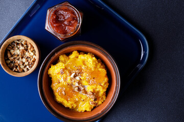 Sweet pumpkin porridge in clay bowl with jam and nuts