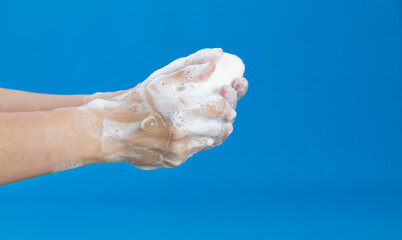 Woman washing hands with soap on blue background