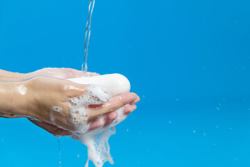 Washing hands and soap with water on blue background