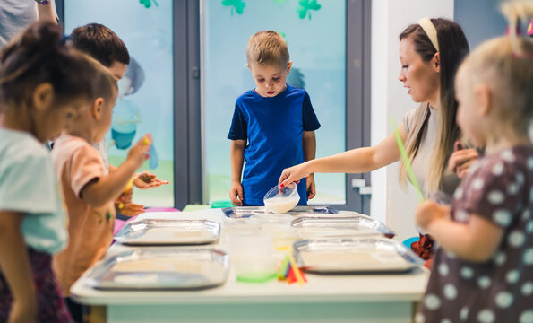 kids and teacher standing around the table and getting ready to paint, nursery. High quality photo