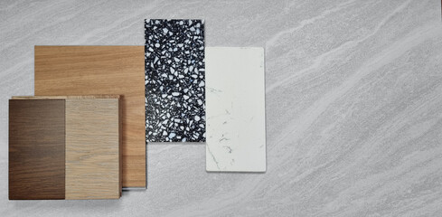 top view moodboard. material samples contains oak and walnut engineering flooring tiles, wooden vinyl tiles, black terrazzo artificial stone, white carrara marble placed on travertine background.