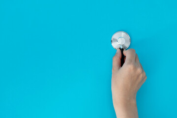 Hand holding a stethoscope on blue background