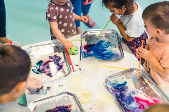 kids painting with small tubes and water paints in the nursery, modern painting techniques. High quality photo