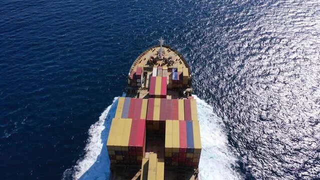 Aerial drone top view video of fully loaded container ship cruising open ocean sea for logistics import export, shipping or transportation