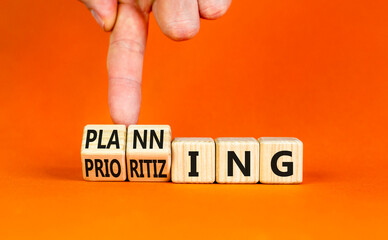 Planning and prioritizing symbol. Concept words Planning and Prioritizing on wooden cubes. Businessman hand. Beautiful orange background. Business planning and prioritizing concept. Copy space.