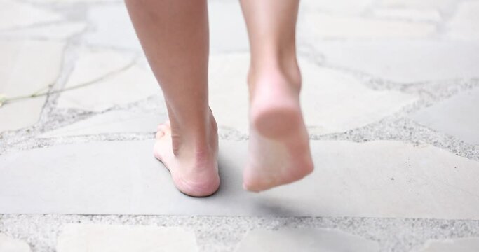 Female legs with red manicure on cement paving stones
