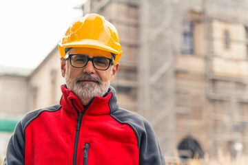 Satisfied with his work caucasian construction worker in his late 50s looking at camera in...