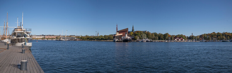 Fototapeta na wymiar Panorama view of a moored smaller cruise ship in the bay Ladugårdsviken and the boat and Vasa museums in the island Djurgården a colorful sunny autumn day in Stockholm