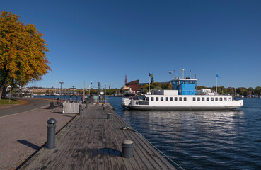 A harbor commuting ferry arriving at the island Skeppsholmen a colorful sunny autumn day in Stockholm