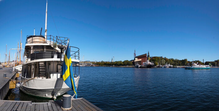 Panorama view of a moored smaller cruise ship in the bay Ladugårdsviken and the boat and Vasa museums in the island Djurgården a colorful sunny autumn day in Stockholm