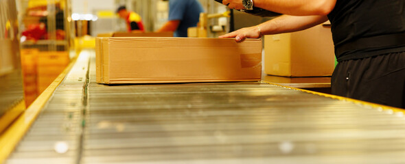 Worker scanning box on conveyor belt in warehouse