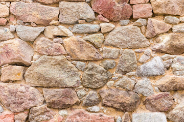 Bunte Mauer aus Sandstein mit großen und kleinen unregelmäßigen Steinen