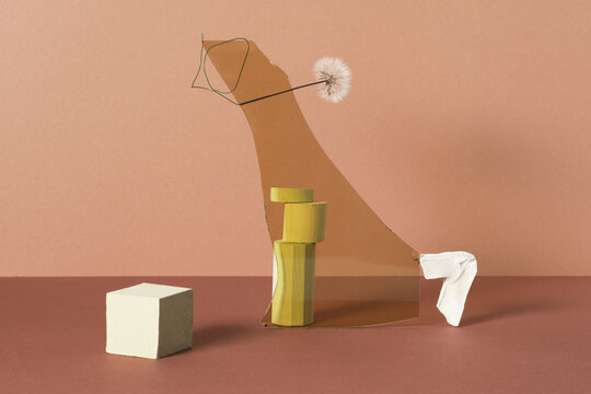 Horizontal studio shot of contemporary still life installation of gypsum and wooden objects, yellow glass and dandelion