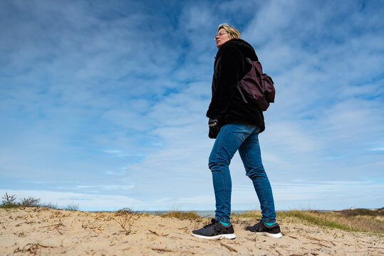 Low angle portrait of a thirty year old woman, standing in the dunes