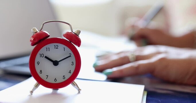 Person is typing on keyboard and red alarm clock