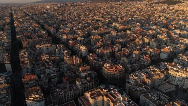 Aerial view of Barcelona city skyline and Sagrada Familia Cathedral at Sunset. Eixample residential famous urban grid. Cityscape with typical urban octagon blocks. Catalonia, Spain 4k Aerial View
