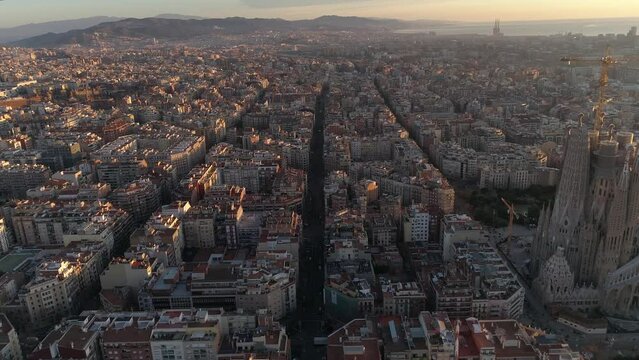 Aerial view of Barcelona city skyline and Sagrada Familia Cathedral at Sunset. Eixample residential famous urban grid. Cityscape with typical urban octagon blocks. Catalonia, Spain 4k Aerial View