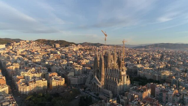 Aerial view of Barcelona city skyline and Sagrada Familia Cathedral at Sunset. Eixample residential famous urban grid. Cityscape with typical urban octagon blocks. Catalonia, Spain 4k Aerial View