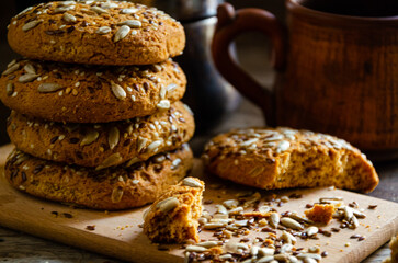 Oatmeal homemade cookies with grains on a wooden board, on the kitchen table and homemade coffee in a clay mug.