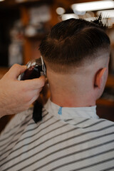 A haircut. Barber cuts a guy's hair in a barbershop close-up with a blurred background