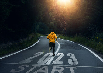 2023 with new ambitions, challenge, plans, goals and visions.  Man running on the mountain road towards new goals in 2023.  - obrazy, fototapety, plakaty