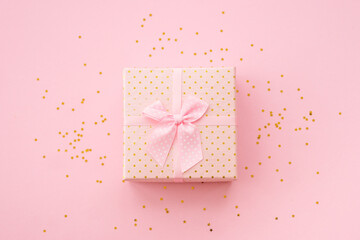 Gift box with ribbon and confetti on pink background. Flat lay image.