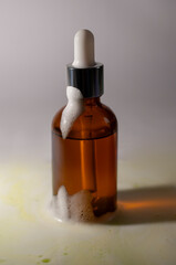 Brown bottle with fluid and foam on top on a light background.