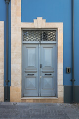 Blue stone wall with gray retro style wooden door in natural stone doorway