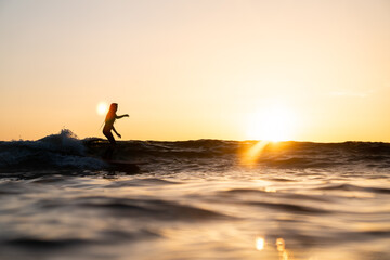 Surfista mujer en atardecer surf ola sobre tabla de surf cielo naranja