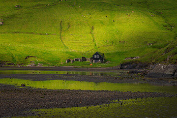 Naklejka premium Saksun is a remote little village on Streymoy island in the wild Faroe Islands. The village is famous for its unique location placed above a jaw-dropping lagoon. 