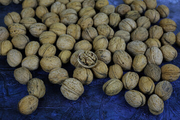 Peeled walnuts. Many closed nuts scattered on a blue background