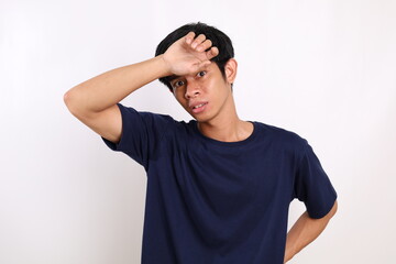 Scared asian young man standing while peeping through his hand. Isolated on white background