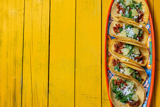 Mexican background with tacos al pastor and mexican sauces. Yellow wooden background, copy space, top view