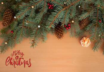Christmas background. Christmas tree branches, gift, balls and cones on wooden texture