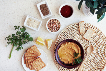 Homemade vegetarian appetizer. Traditional hummus with grain cookies, parsley, lemon slices. Parsley, paprika, roman cumin seeds, chickpeas, sesame ingredients