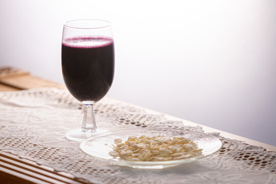 Grape juice in wine glass on table with unleavened matzah bread on lace for Christian church communion 