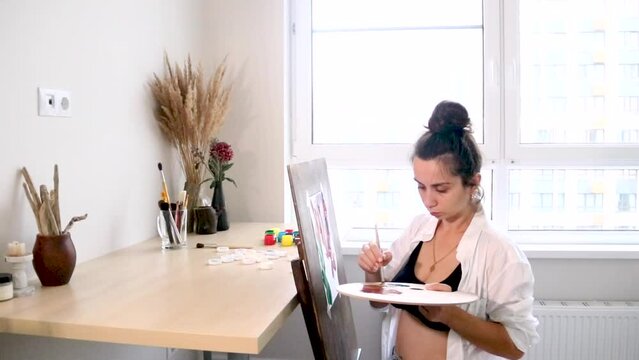 a girl artist paints a picture at home on an easel