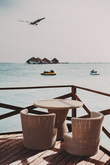 A vertical shot of a wicker table and chairs of a street bar of a luxury Maldives resort in the...