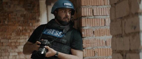 Hispanic male war journalist wearing protective helmet and bulletproof vest gear taking photos...