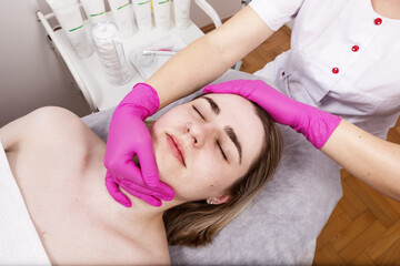 Obraz na płótnie Canvas Beautiful girl with piercing doing facial massage in a beauty salon