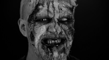 Close-up macro frightening man face with Halloween zombie blood flows and drips on face, trying to...