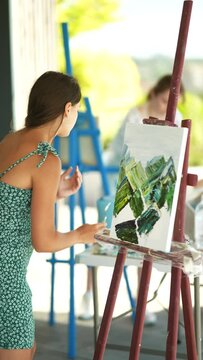 Young woman artist paints with a spatula on the canvas