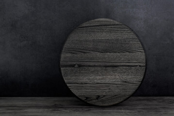 Blank round wood sign with copy space stand on black wooden table. Simple Mockup door circle sign.