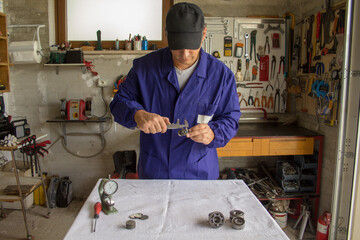 Hands of a mechanic who in his workshop measures a car cross with a caliber. Precision mechanics.
