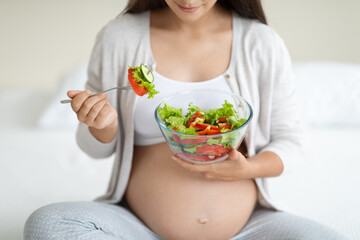 Cropped of pregnant woman eating healthy vegetable salad at home