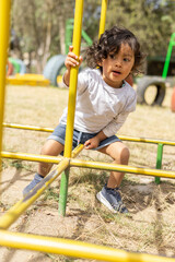 playing in a park adorable little latin girl with curly hair, wear casual and summer clothes, childhood and lifestyle having fun