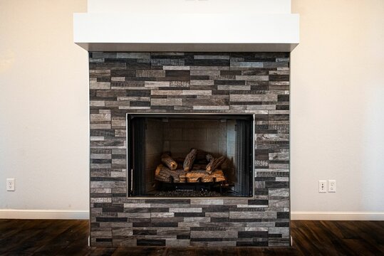 Gray fireplace with unlit firewood inside on a white background of living  room wall