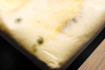 part of a pack of spoiled butter with mold on a wooden board