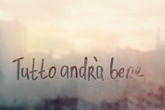 Lettering Italian text Tutto andra bene everything will be fine in english on sunset wet window
